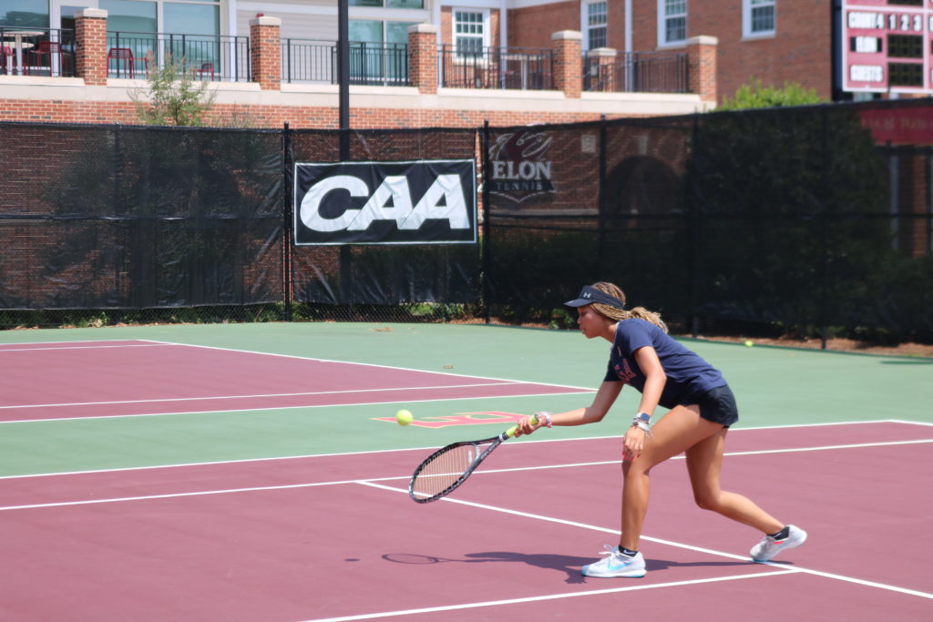 Camper practices her forehand against another player.